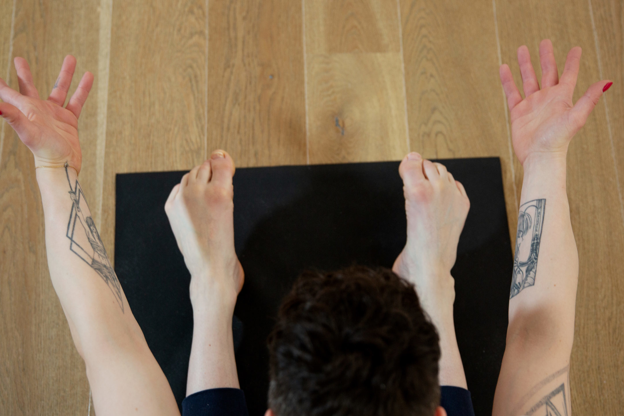 Auf Yogamatte Arme und Beine im Sitzen nach vorne ausgestreckt