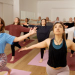 Yoga Dance Flow Klasse in stehender Position mit seitlich ausgestreckten Armen